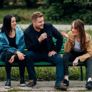 Three people sitting on a bench chatting